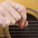 Index finger pointing down on pick in how to hold a guitar pick lesson